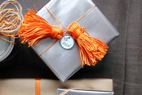 Подарок в серебристой упаковке с оранжевыми кистями