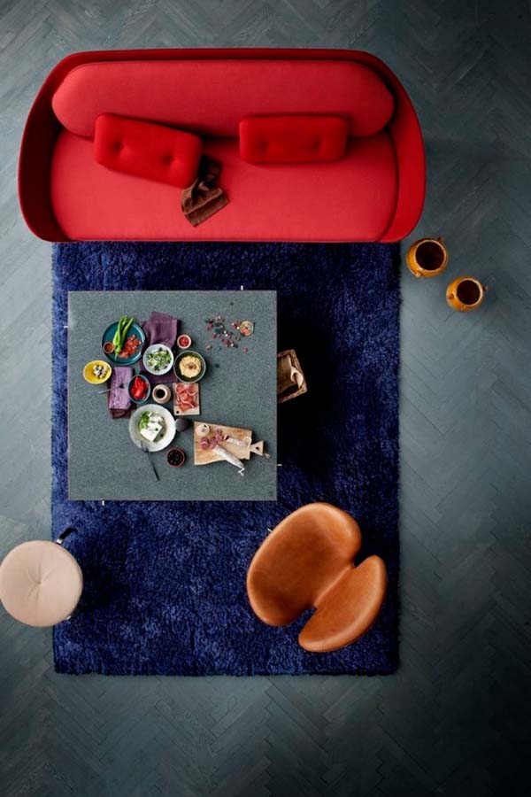 Красный мягкий диван на синем ковре в гостиной