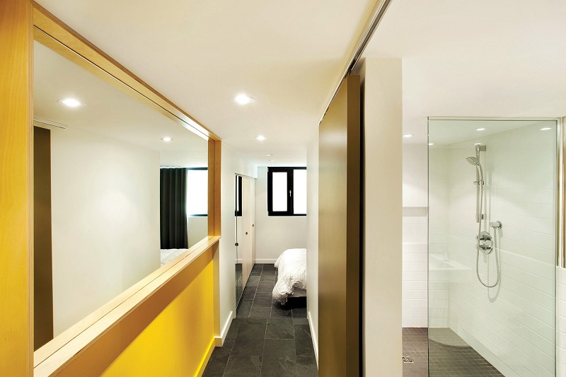 Коридор из ванной в спальню с огромным зеркалом и ярко-жёлтыми панелями стен