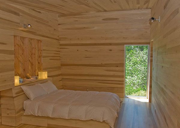 Светлая постель в спальне с деревянной отделкой