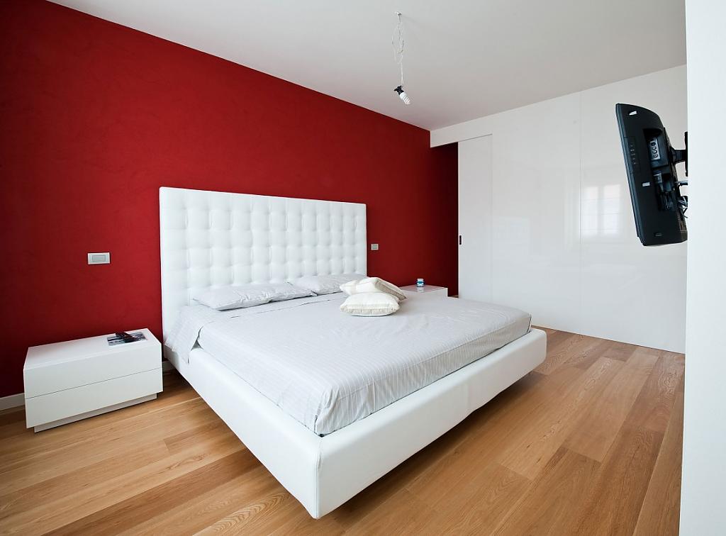 Красная стена и белая кровать в спальне